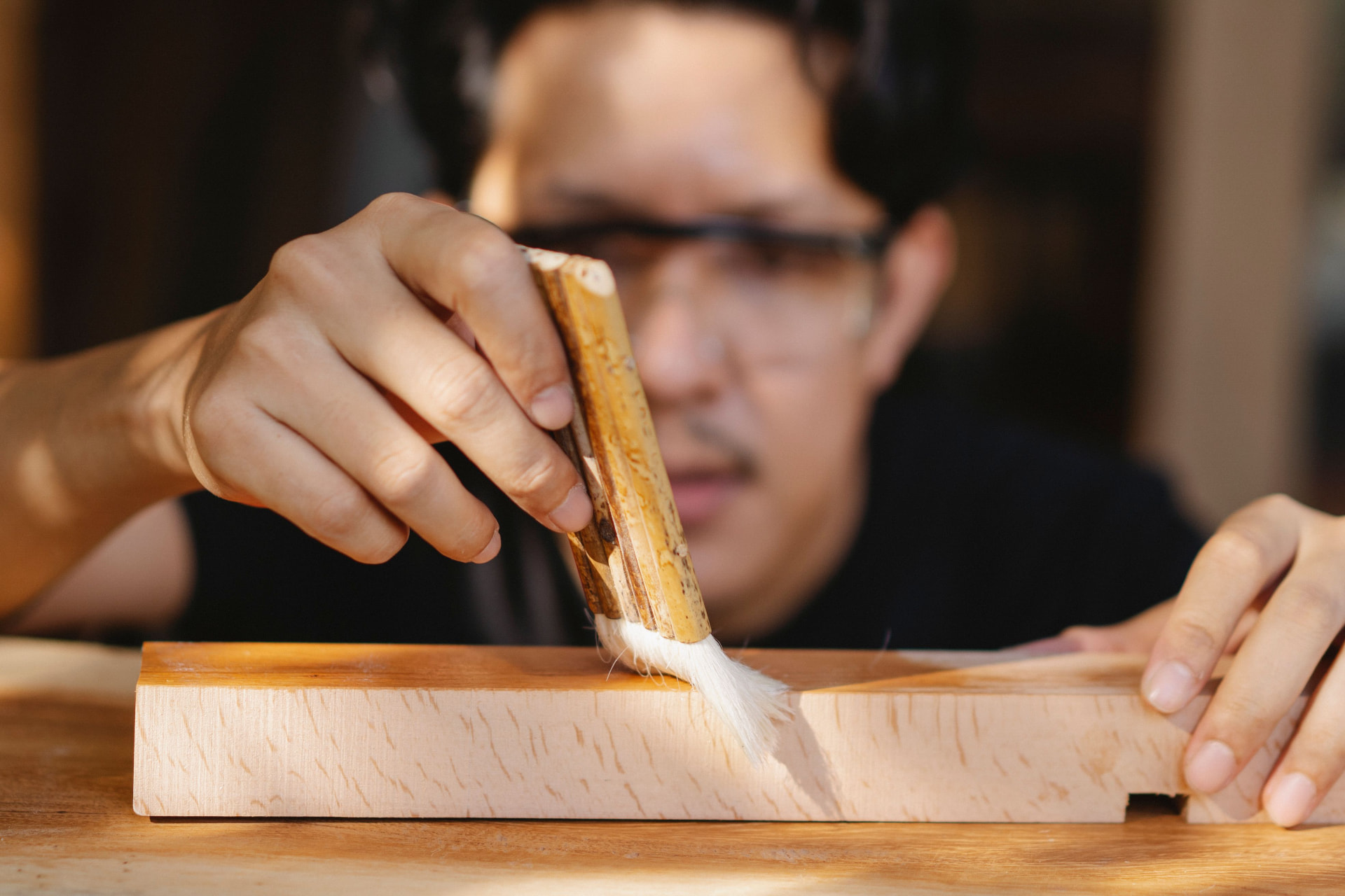Artigiano che passa un pennello su un pezzo di legno
